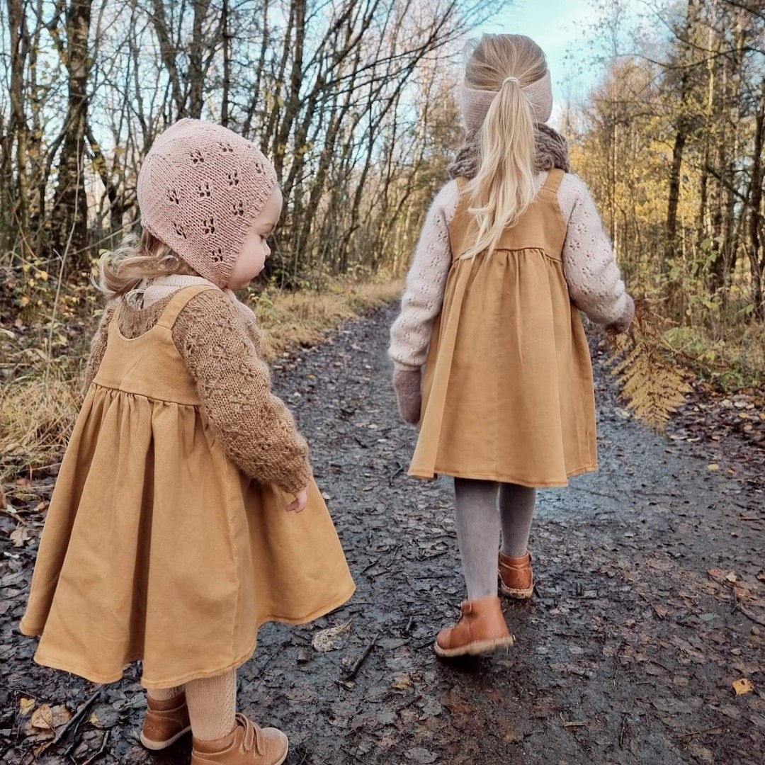 Barn ikledd strikketøy som går i skog.